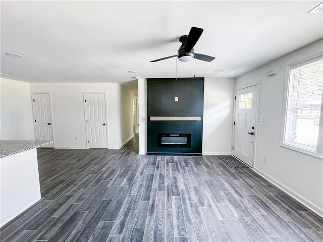 unfurnished living room featuring a fireplace, ceiling fan, and dark hardwood / wood-style flooring