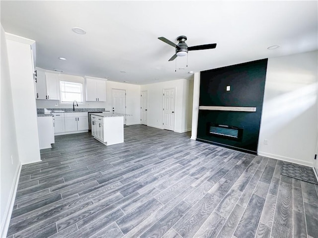 kitchen featuring ceiling fan, sink, wood-type flooring, a center island, and white cabinetry