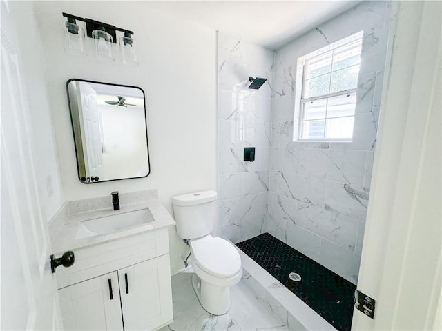 bathroom with tiled shower, vanity, and toilet