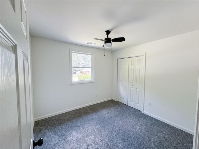 unfurnished bedroom with dark colored carpet, a closet, and ceiling fan