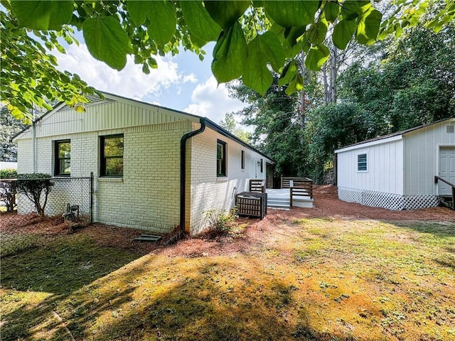 view of side of home with a lawn, a wooden deck, and a storage shed