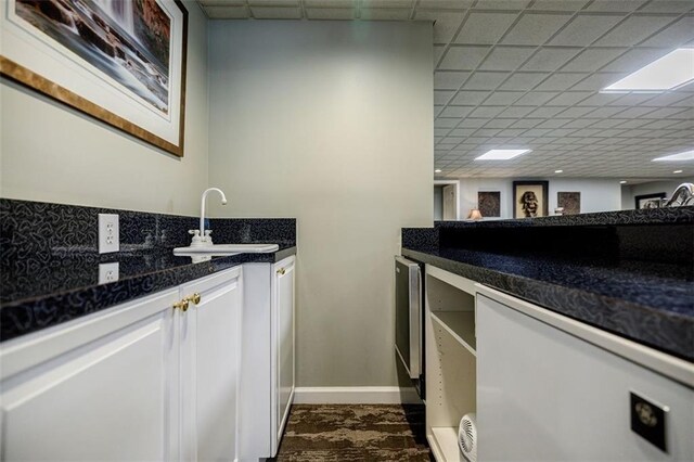 5318 Brooke Farm Dr, Dunwoody, GA 30338 - kitchen with a drop ceiling, a sink, dark countertops, baseboards, and white cabinets