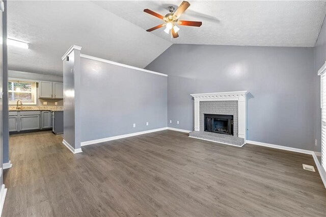 unfurnished living room featuring a fireplace, dark wood-type flooring, a sink, ceiling fan, and baseboards