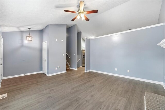 unfurnished living room with lofted ceiling, wood finished floors, a ceiling fan, baseboards, and stairway