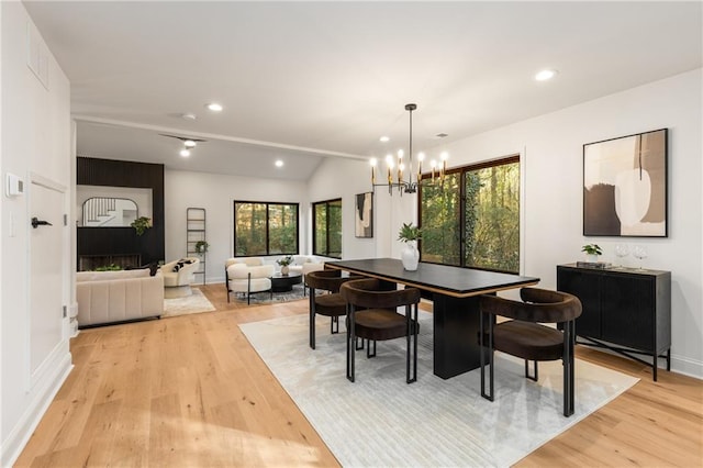 dining space with vaulted ceiling, plenty of natural light, a notable chandelier, and light hardwood / wood-style floors