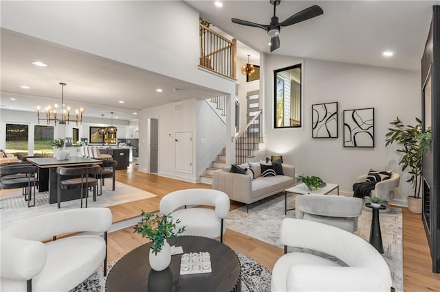 living room with ceiling fan with notable chandelier and light hardwood / wood-style flooring