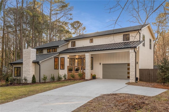 modern farmhouse featuring a porch, a garage, and a front lawn