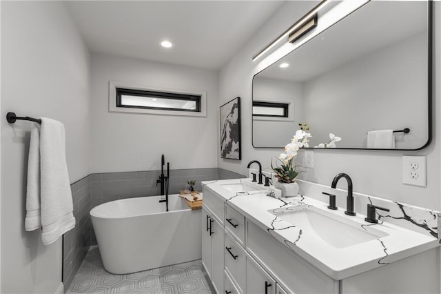 bathroom featuring tile patterned floors, vanity, tile walls, and a tub