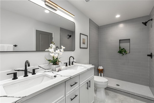 bathroom featuring vanity, toilet, tile patterned flooring, and a tile shower