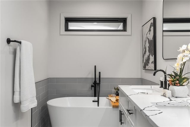 bathroom with vanity, tile walls, and a washtub