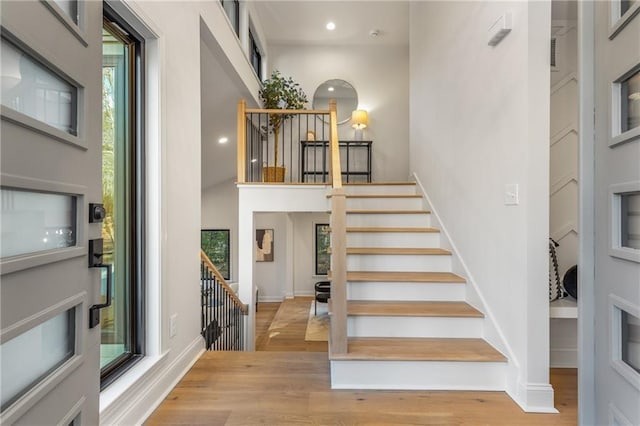 staircase featuring a towering ceiling and wood-type flooring