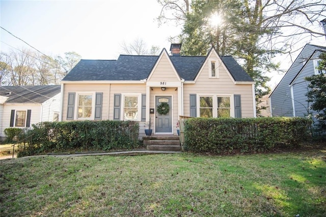 view of front facade featuring a front yard, roof with shingles, and a chimney