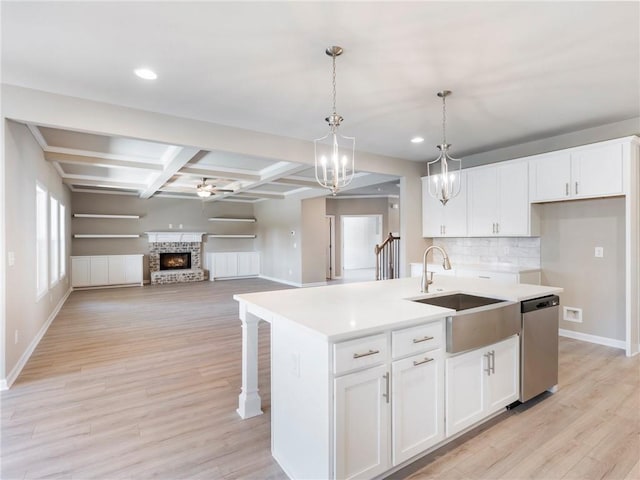 kitchen with white cabinetry, sink, coffered ceiling, a kitchen island with sink, and beam ceiling