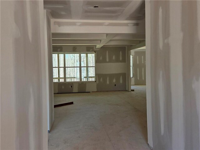 unfurnished living room featuring beam ceiling, coffered ceiling, and light wood-type flooring