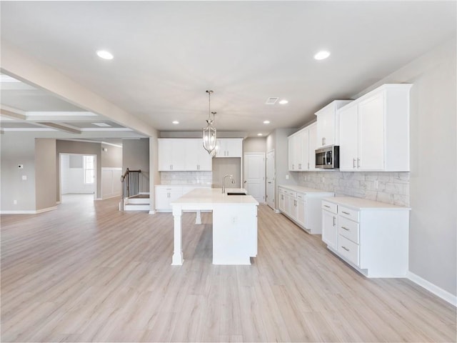 unfurnished living room with coffered ceiling, a fireplace, ceiling fan with notable chandelier, beamed ceiling, and light wood-type flooring