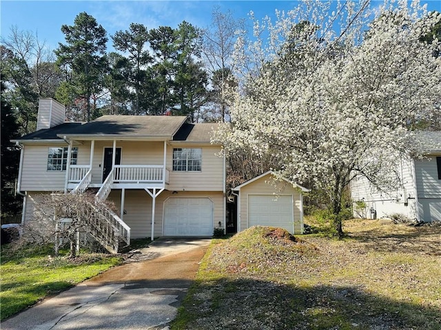 view of front of property with driveway, stairway, covered porch, an attached garage, and a chimney