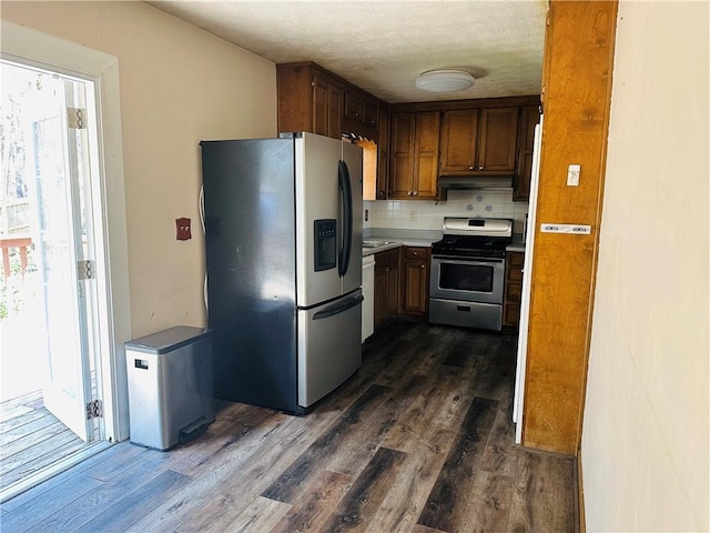 kitchen with dark wood-style floors, stainless steel appliances, light countertops, a textured ceiling, and backsplash