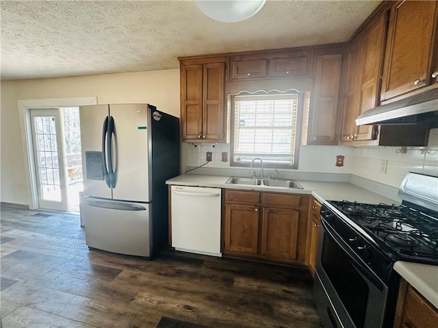 kitchen featuring under cabinet range hood, brown cabinets, stainless steel appliances, and a sink