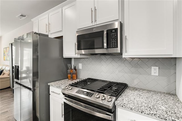 1590 Ridgebrook Downs, Mableton, GA 30126 - kitchen featuring stainless steel appliances, white cabinetry, light stone countertops, backsplash, and light wood-type flooring