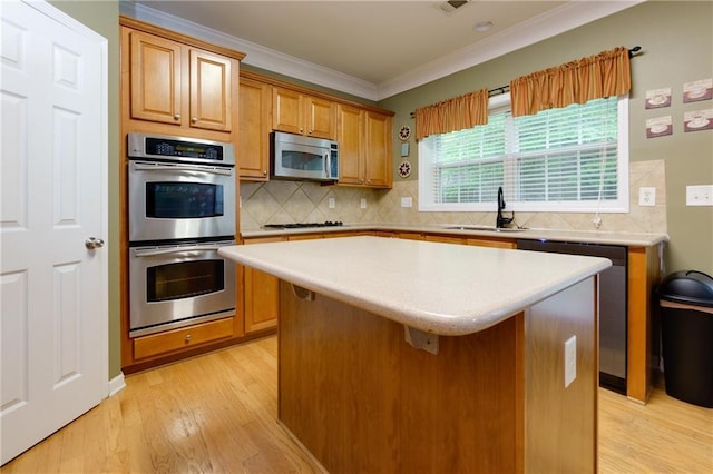 118 Brendylynn Trce, Woodstock, GA 30188 - kitchen featuring appliances with stainless steel finishes, a sink, crown molding, light wood-type flooring, and a kitchen island