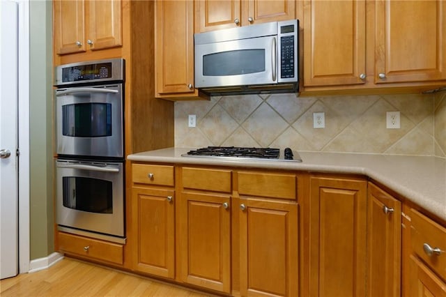 118 Brendylynn Trce, Woodstock, GA 30188 - kitchen with appliances with stainless steel finishes, tasteful backsplash, light wood-style floors, light countertops, and brown cabinets
