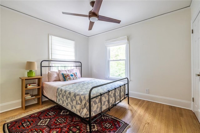 bedroom featuring light wood finished floors, ornamental molding, baseboards, and ceiling fan