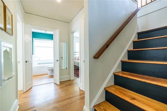 staircase featuring wood finished floors and baseboards