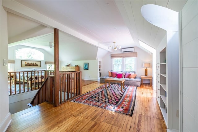 living room featuring an AC wall unit, wood-type flooring, vaulted ceiling, and baseboards