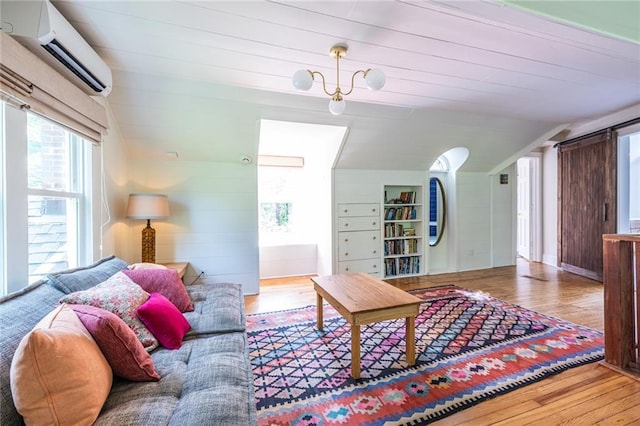 living area with a wall mounted AC, vaulted ceiling, and wood finished floors
