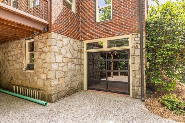 view of exterior entry featuring stone siding and brick siding