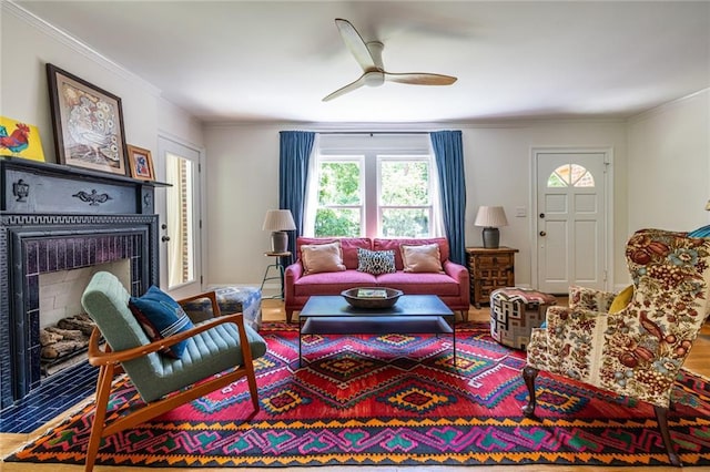 living area with a fireplace, a ceiling fan, and crown molding