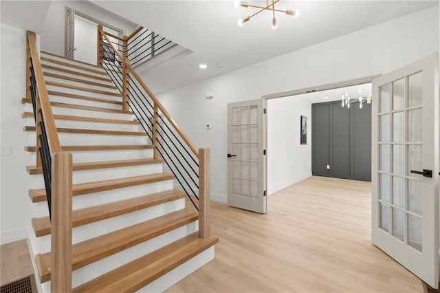 stairs with a chandelier, french doors, wood finished floors, baseboards, and recessed lighting