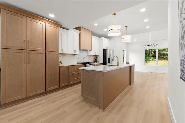 kitchen with appliances with stainless steel finishes, light wood-style flooring, recessed lighting, a sink, and an island with sink