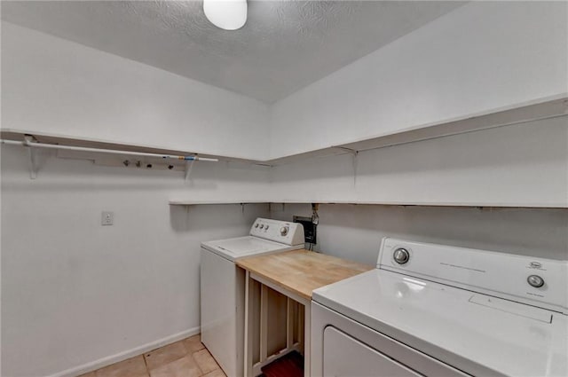 washroom featuring light tile patterned flooring, separate washer and dryer, and a textured ceiling