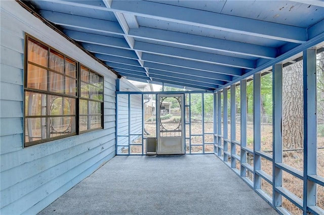 unfurnished sunroom featuring lofted ceiling with beams