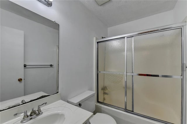 full bathroom featuring vanity, a textured ceiling, enclosed tub / shower combo, and toilet