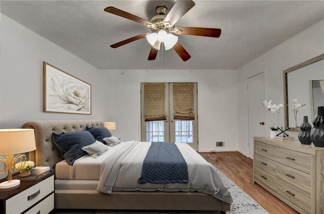 bedroom with wood-type flooring, ceiling fan, and french doors