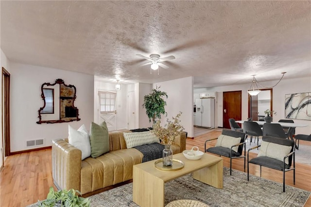 living room featuring light wood-type flooring and a textured ceiling