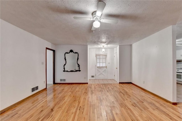 spare room featuring ceiling fan, a textured ceiling, and light hardwood / wood-style flooring