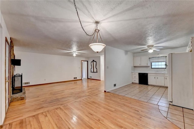 kitchen featuring pendant lighting, dishwasher, white refrigerator, white cabinets, and light wood-type flooring