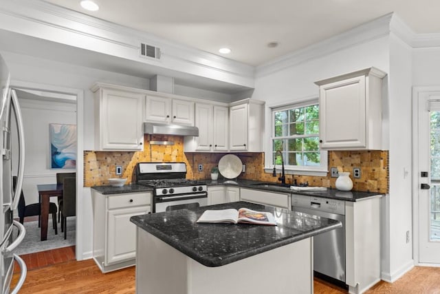 3242 Monarch Pine Dr, Peachtree Corners, GA 30071 - kitchen featuring appliances with stainless steel finishes, under cabinet range hood, white cabinetry, ornamental molding, and light wood-style flooring