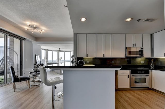 285 Centennial Olympic Park Dr NW Unit 1905, Atlanta, GA 30339 - kitchen featuring appliances with stainless steel finishes, dark countertops, light wood-style floors, backsplash, and recessed lighting