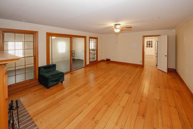 unfurnished living room featuring light wood-style floors, crown molding, baseboards, and a ceiling fan