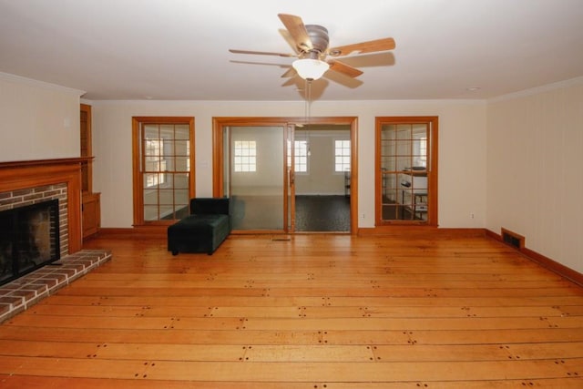 unfurnished living room featuring visible vents, a ceiling fan, hardwood / wood-style flooring, crown molding, and a brick fireplace