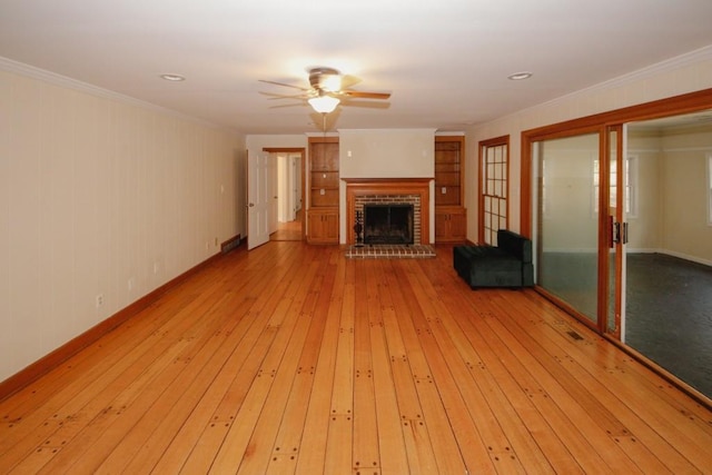 unfurnished living room with ornamental molding, light wood-type flooring, a fireplace, and ceiling fan