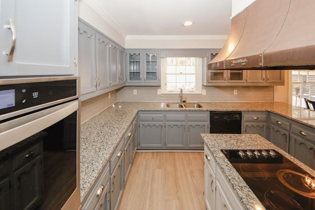 kitchen with crown molding, decorative backsplash, a sink, island range hood, and black appliances