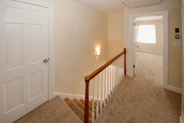 hall with baseboards, light carpet, and an upstairs landing