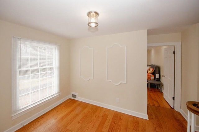 spare room featuring visible vents, light wood-style flooring, and baseboards