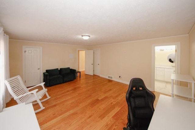 office area featuring ornamental molding, light wood-type flooring, visible vents, and baseboards