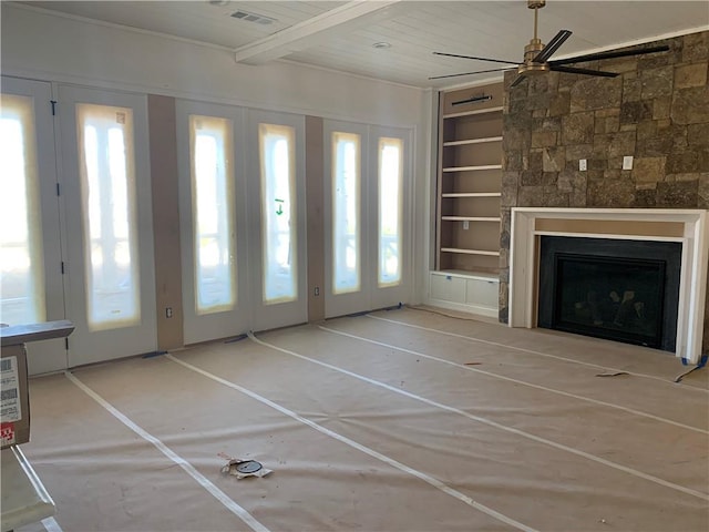 unfurnished living room with built in shelves, a fireplace, visible vents, a ceiling fan, and beam ceiling